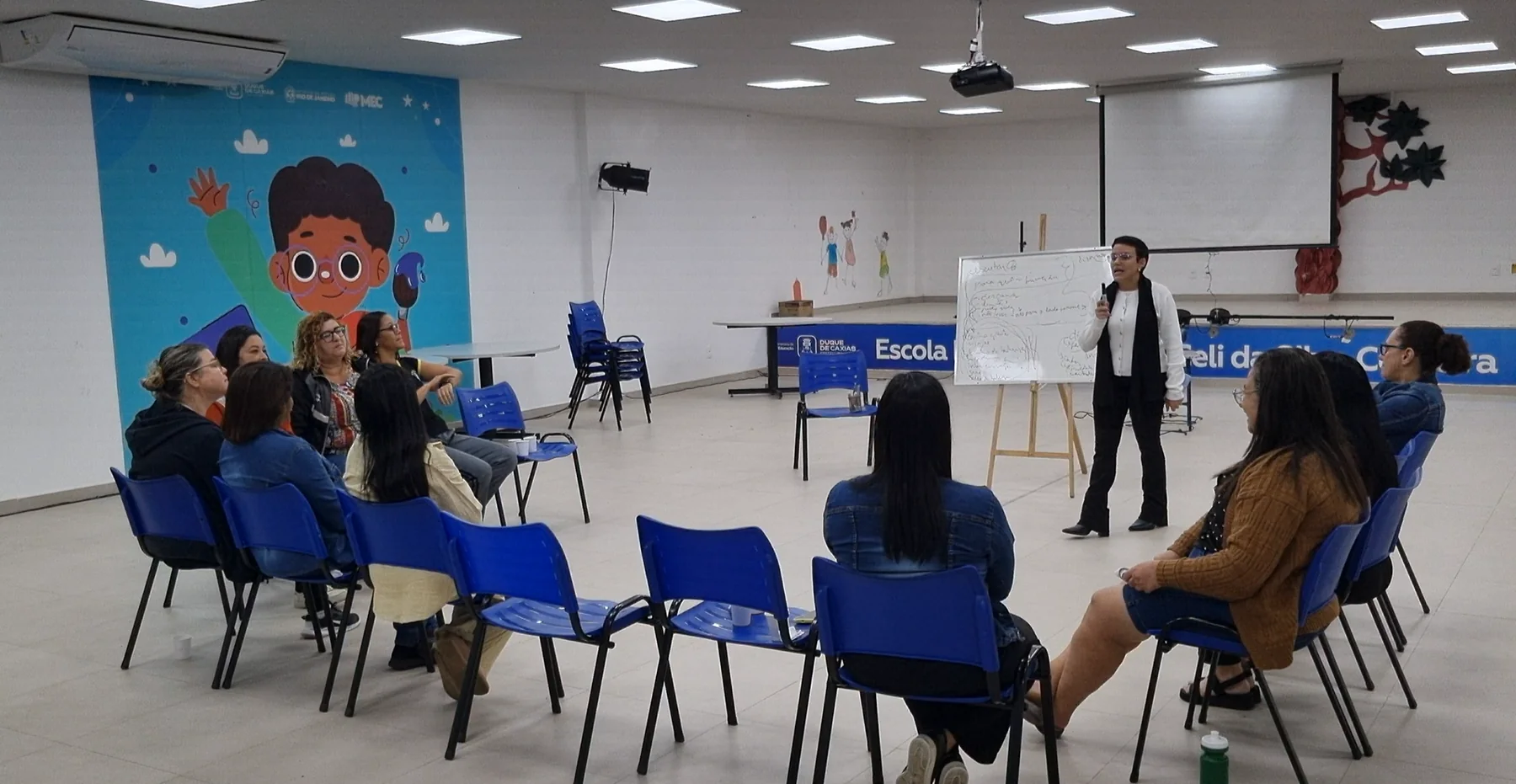 Thaís conduzindo um encontro com profissionais de uma escola